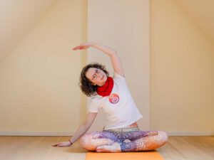 Carola Schmidt, zertifizierte Kundalini Yoga Lehrerin, praktiziert Yoga und lächelt in die Kamera.